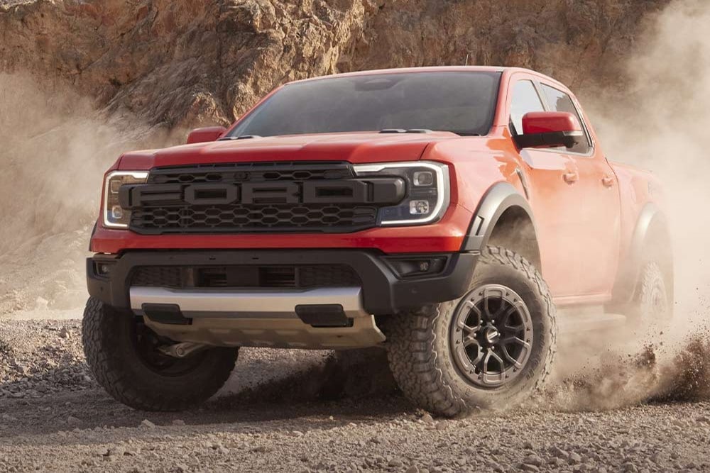 Een rode Ford Ranger doet stof opwaaien door een woestijnlandschap.