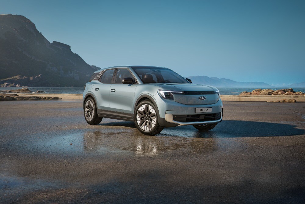 Een grijze Ford Explorer op een nat strand onder een blauwe hemel.