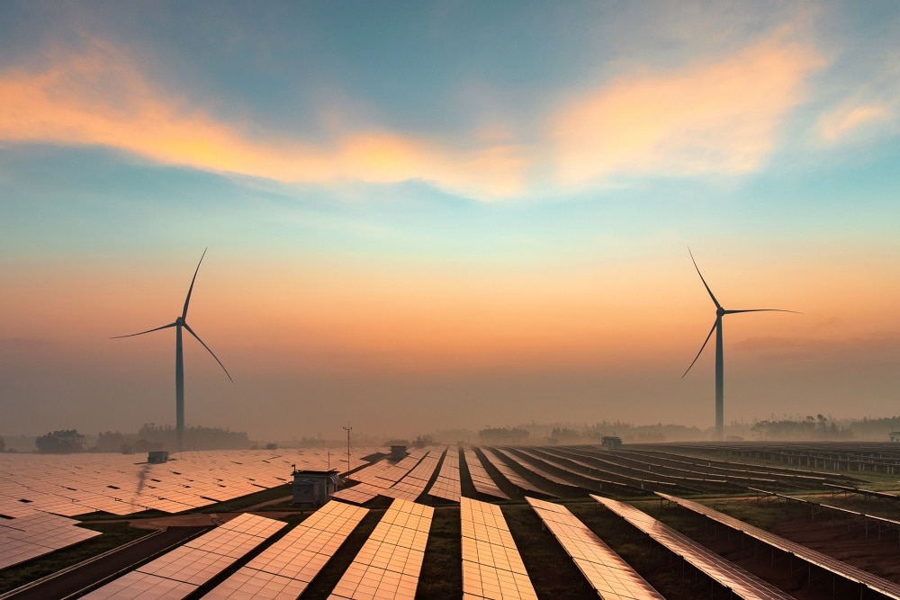 Hernieuwbare energiebronnen, waaronder windturbines en zonnepanelen, bij zonsondergang.