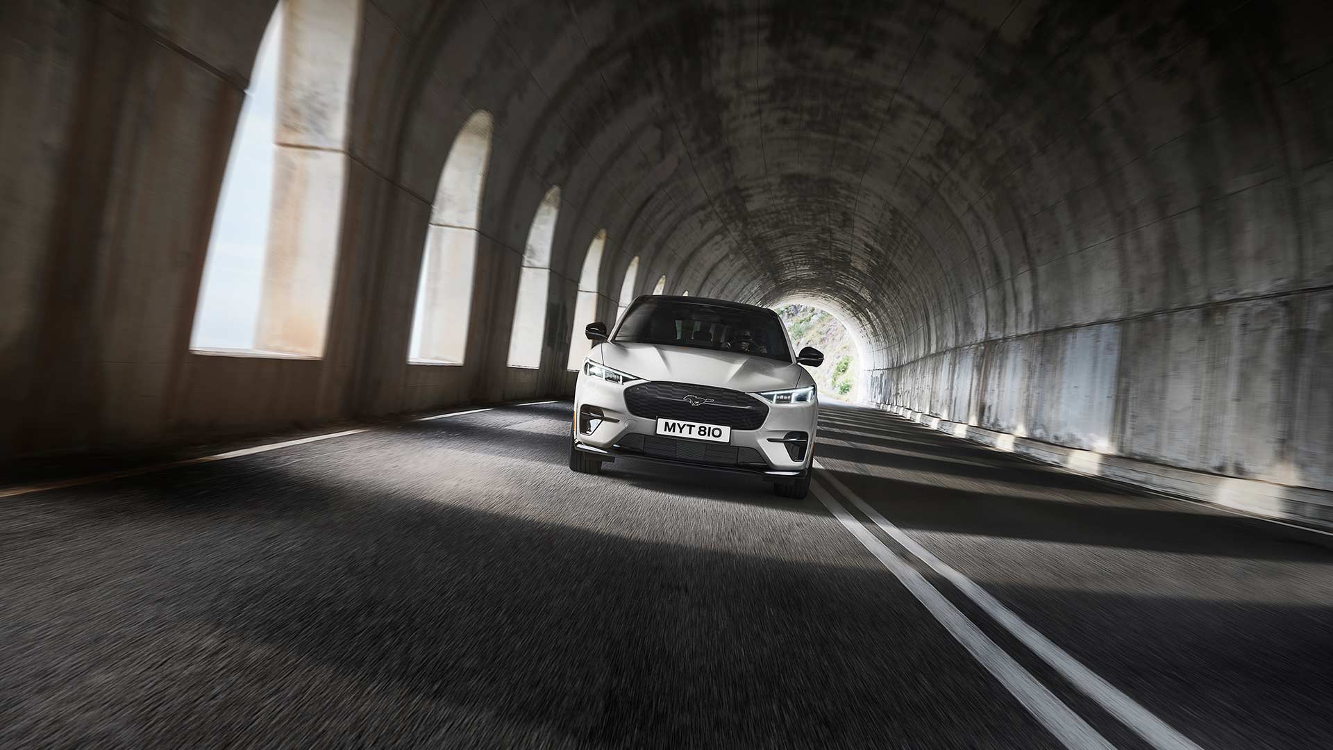 Een zilveren Ford Mustang Mach-E elektrische auto die door een tunnel rijdt.