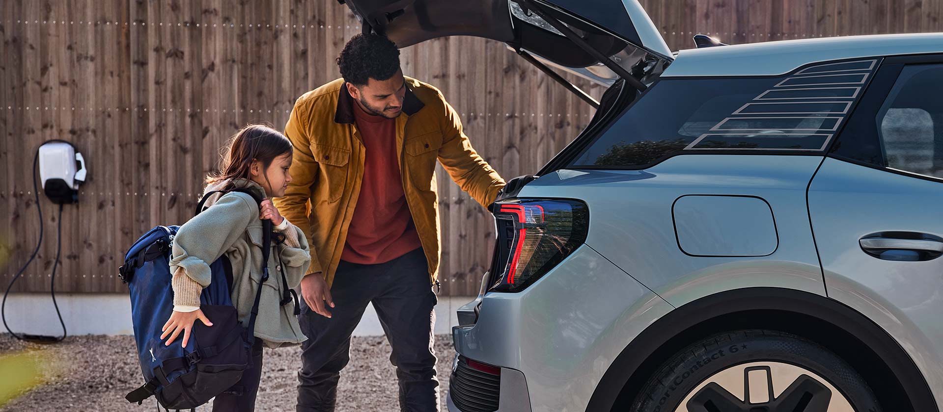 Een familie die de kofferbak van een blauwe elektrische Ford Explorer aan het laden is.