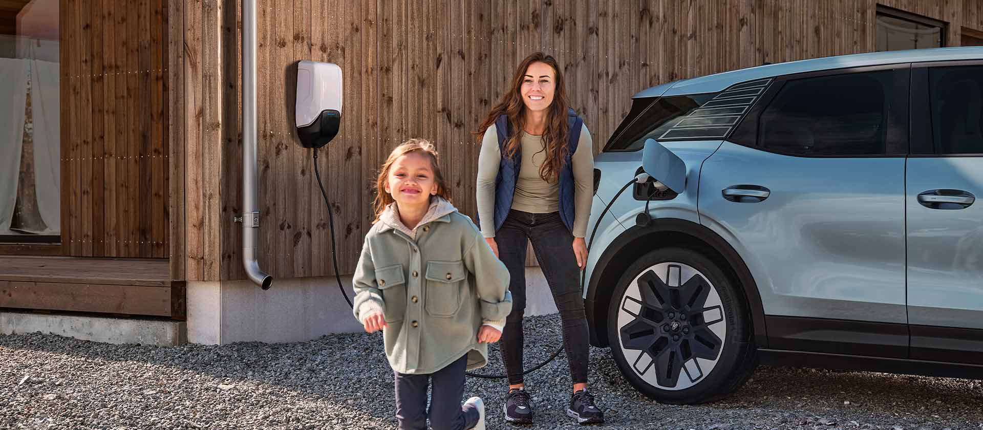 Een gezin dat plezier heeft terwijl ze hun elektrische Ford Explorer opladen met een EV-thuislader buitenshuis.