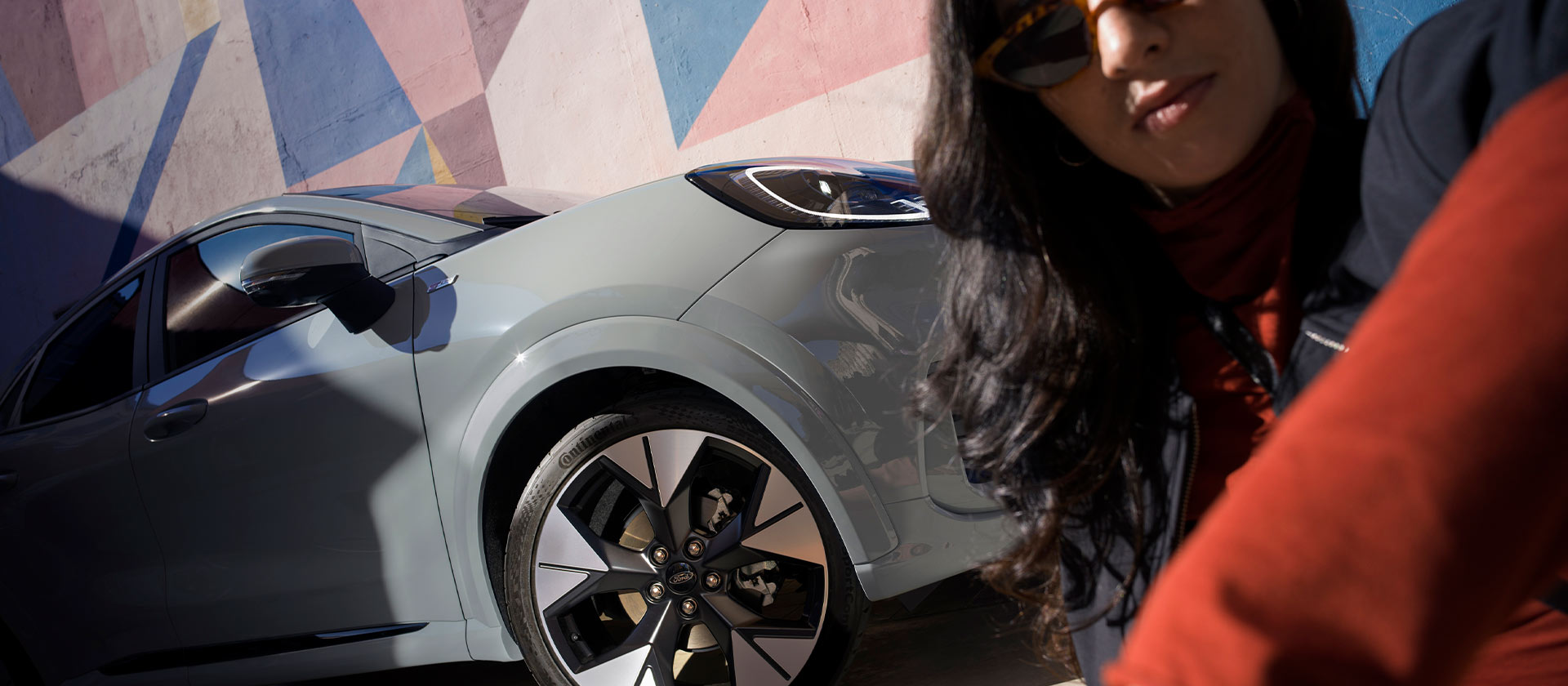 Een persoon die naast een zilveren Ford Puma Mild Hybrid auto zit.