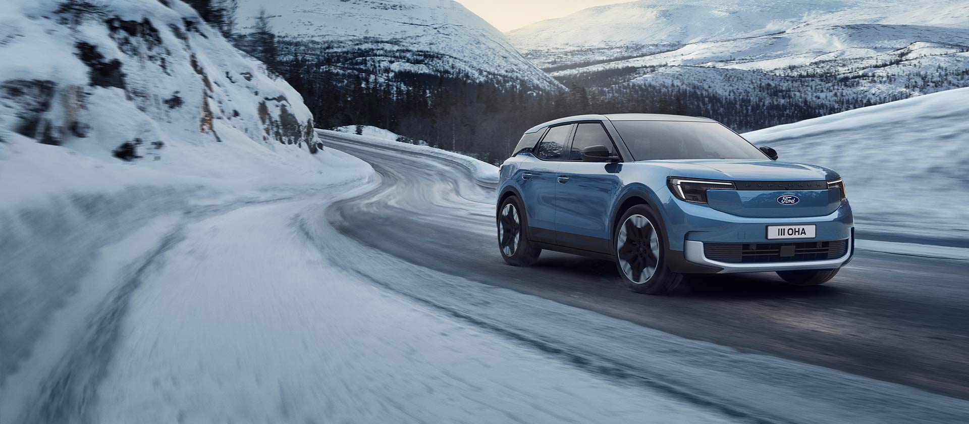 Blue electric Ford Explorer on a snowy mountain road, highlighting its capability and range in winter conditions.