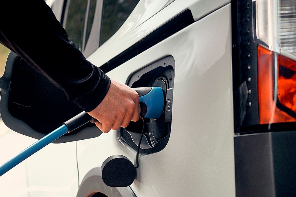 Een persoon die een elektrische Ford-voertuig aansluit op een EV-oplaadkabel.