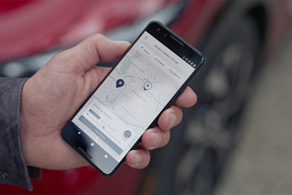 Een smartphone die de FordPass™-app weergeeft met nabijgelegen laadpunten voor openbaar laden van Ford EV's.