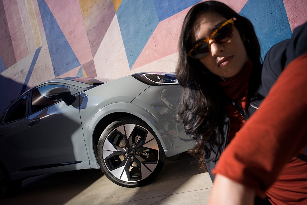 Een persoon die naast een zilveren Ford Puma Mild Hybrid auto zit.
