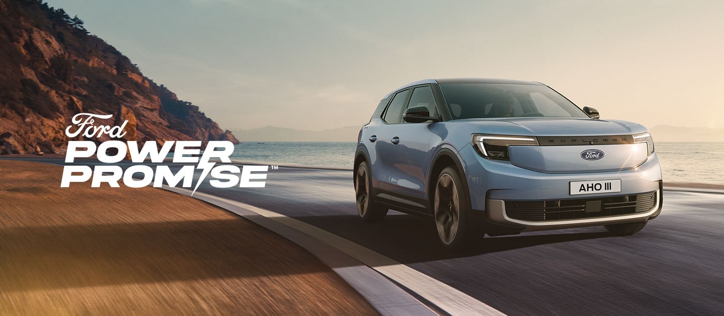 Een blauwe elektrische Ford Explorer rijdt langs een kustweg in de schemering.
