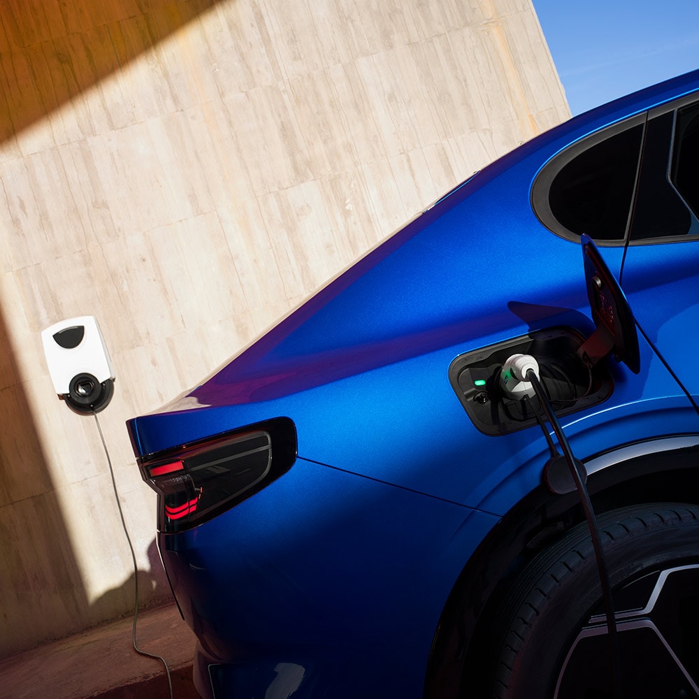Een achteraanzicht van een blauwe Ford Capri elektrische auto aangesloten op een EV-thuislaadpunt