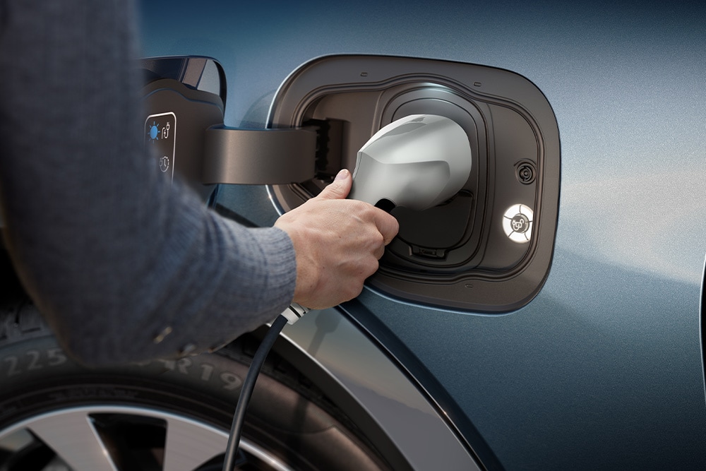 Een close-up van iemand die een elektrisch voertuig van Ford oplaadt.