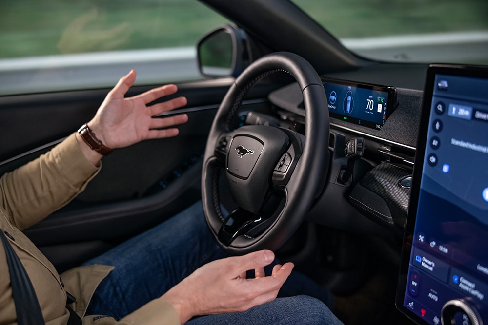 A person in the driver's seat of a car with their hands off the steering wheel.