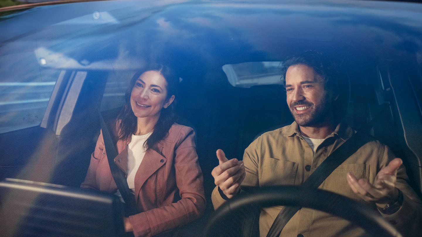 Two people sitting in the front seats of a Ford vehicle, both wearing seatbelts.