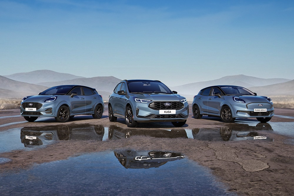 Een Ford Puma, Ford Kuga en Ford Puma Gen-E geparkeerd op een natte weg met bergen op de achtergrond.