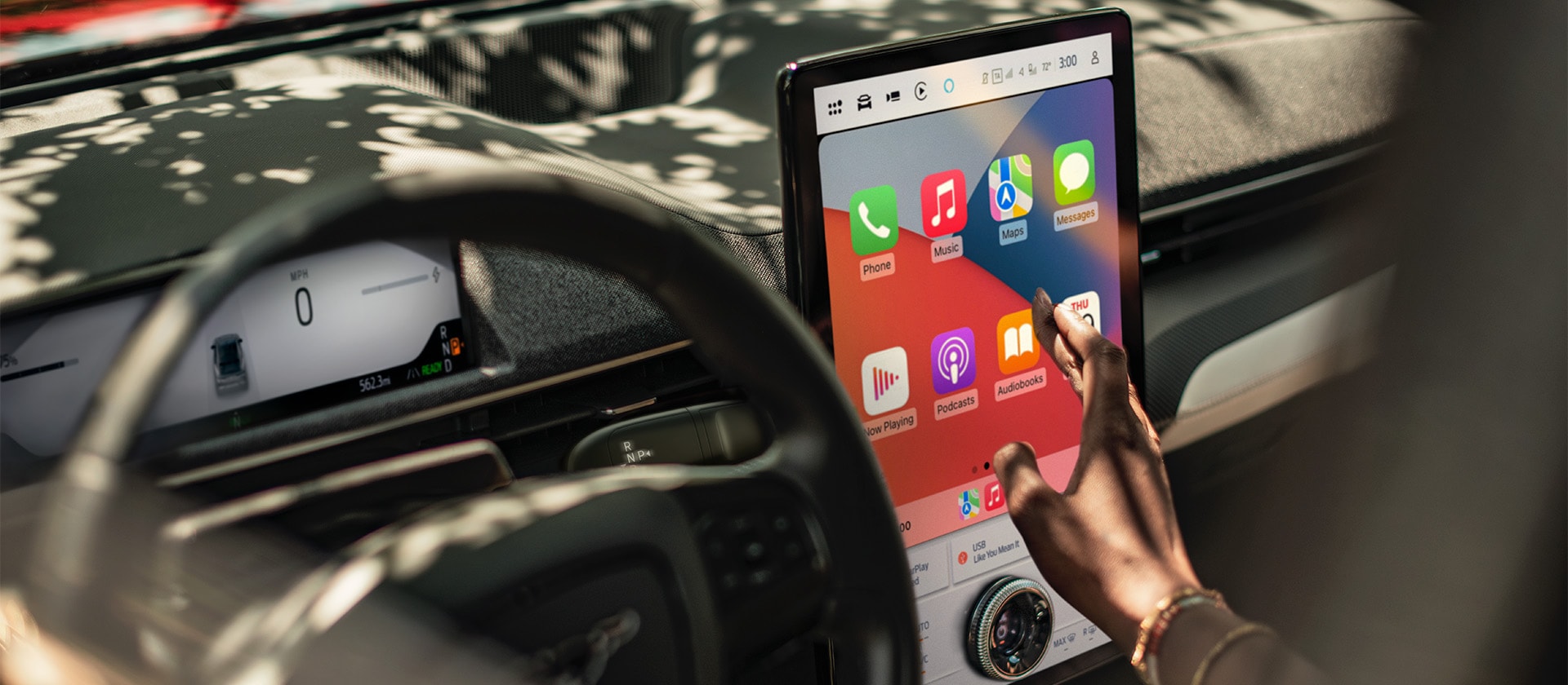 Een close-up van de bestuurder van een Ford Mustang Mach-E die het grote 15.5" SYNC 4-touchscreen met Apple CarPlay gebruikt. 
