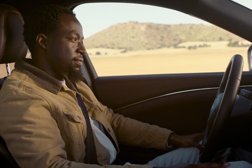 Een man rijdt in een Ford Mustang Mach-E met BlueCruise 'Hands off, eyes on' technologie.