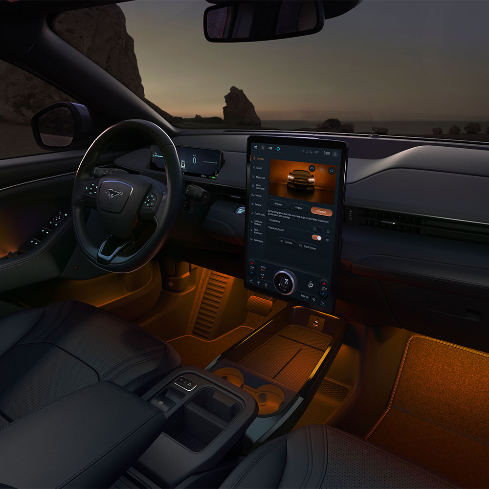 Het interieur van de Ford Mustang Mach-E in het donker, met het 15.5" SYNC 4-touchscreen en de omgevingsledverlichting ingesteld op oranje.