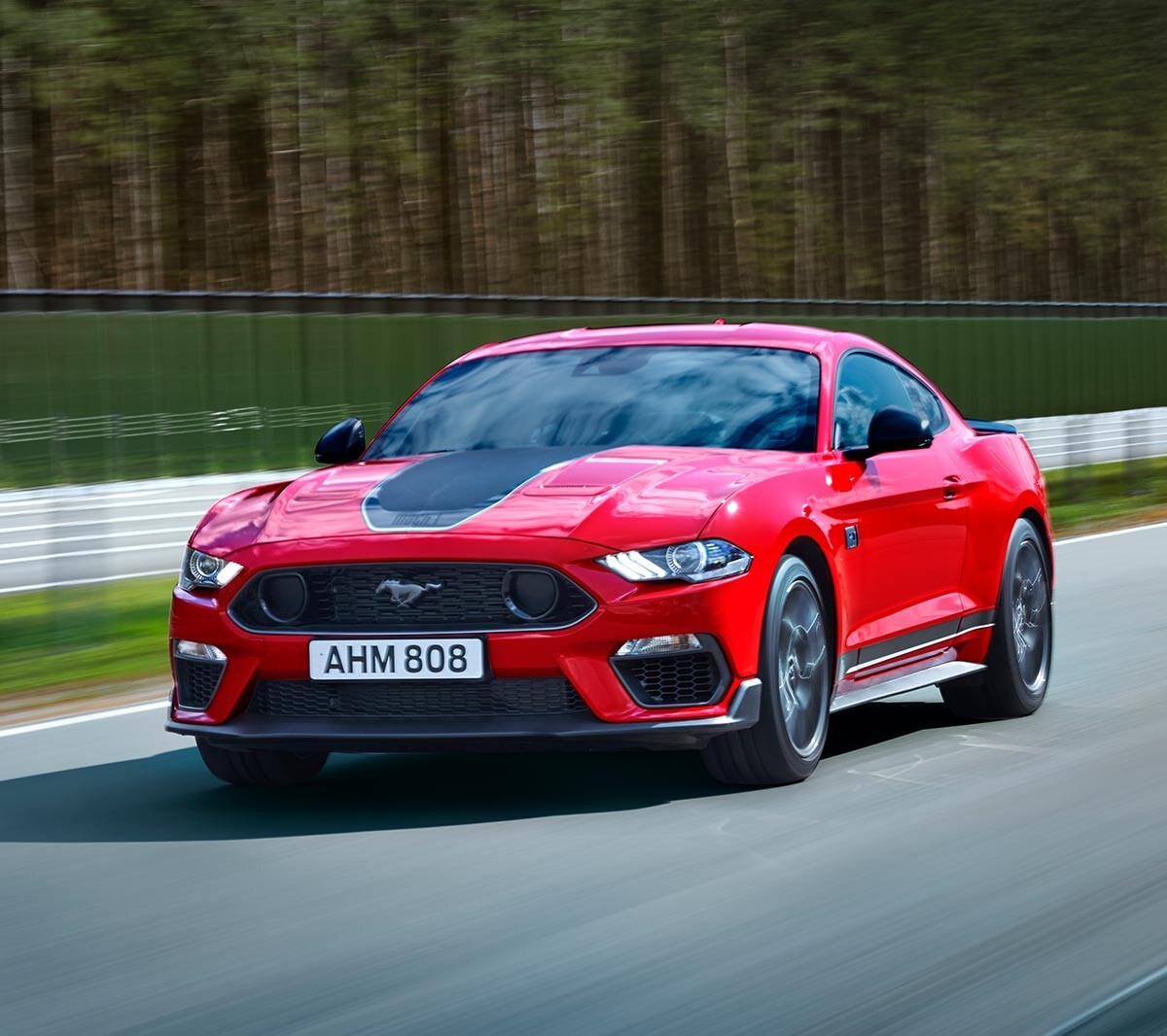 Ford Mustang Mach 1 driving on a racetrack.