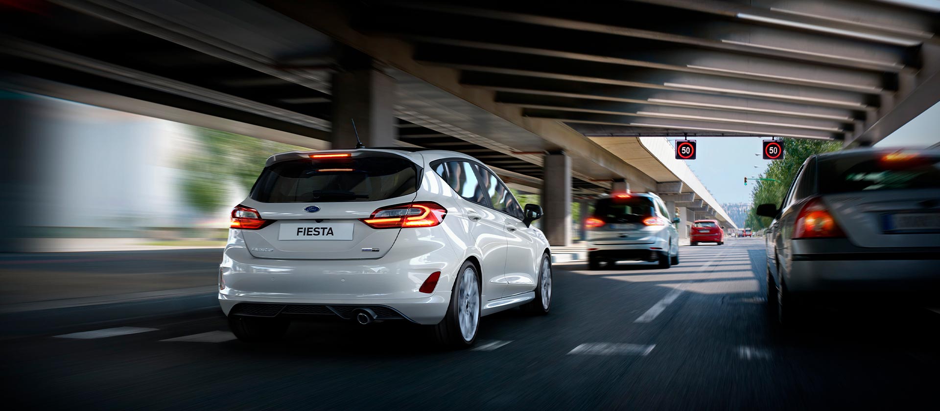 Een zilverkleurige Ford Fiesta rijdt langs een snelweg.
