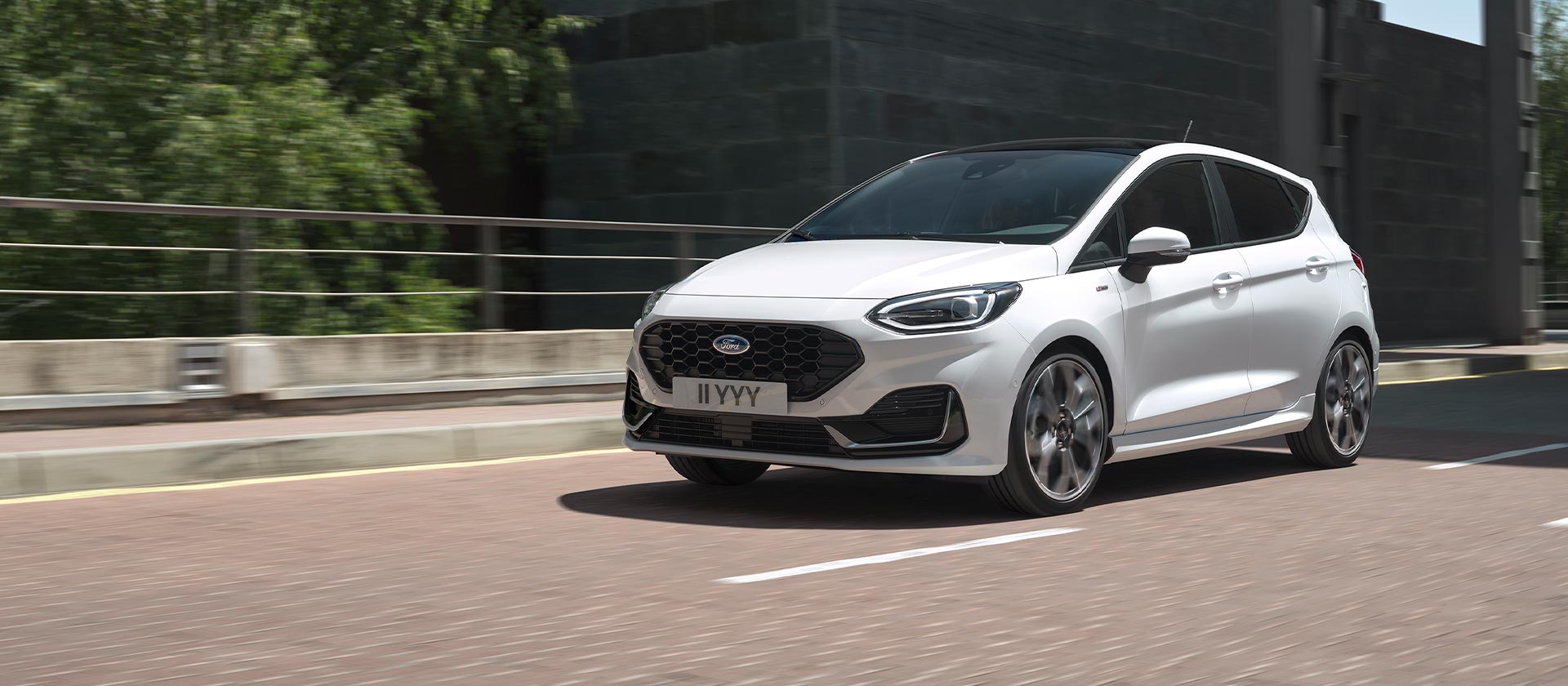 Witte Ford Fiesta die rijdt in een stad.
