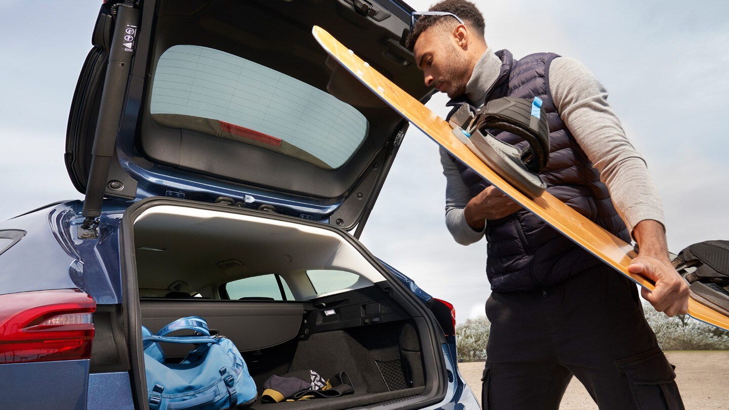 Man loading things into an open trunk of a Ford Focus
