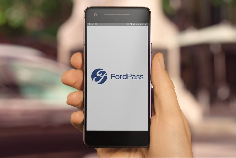 Hand met mobiele telefoon waarop de Ford-app te zien is