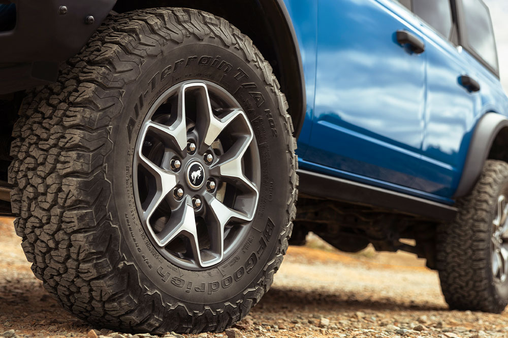Een close-up van de all-terrainbanden van een blauwe Ford Bronco.