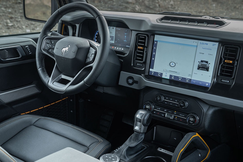 Aanzicht van het Ford Bronco interieur, inclusief het lederen stuurwiel en het verbonden touchpad.