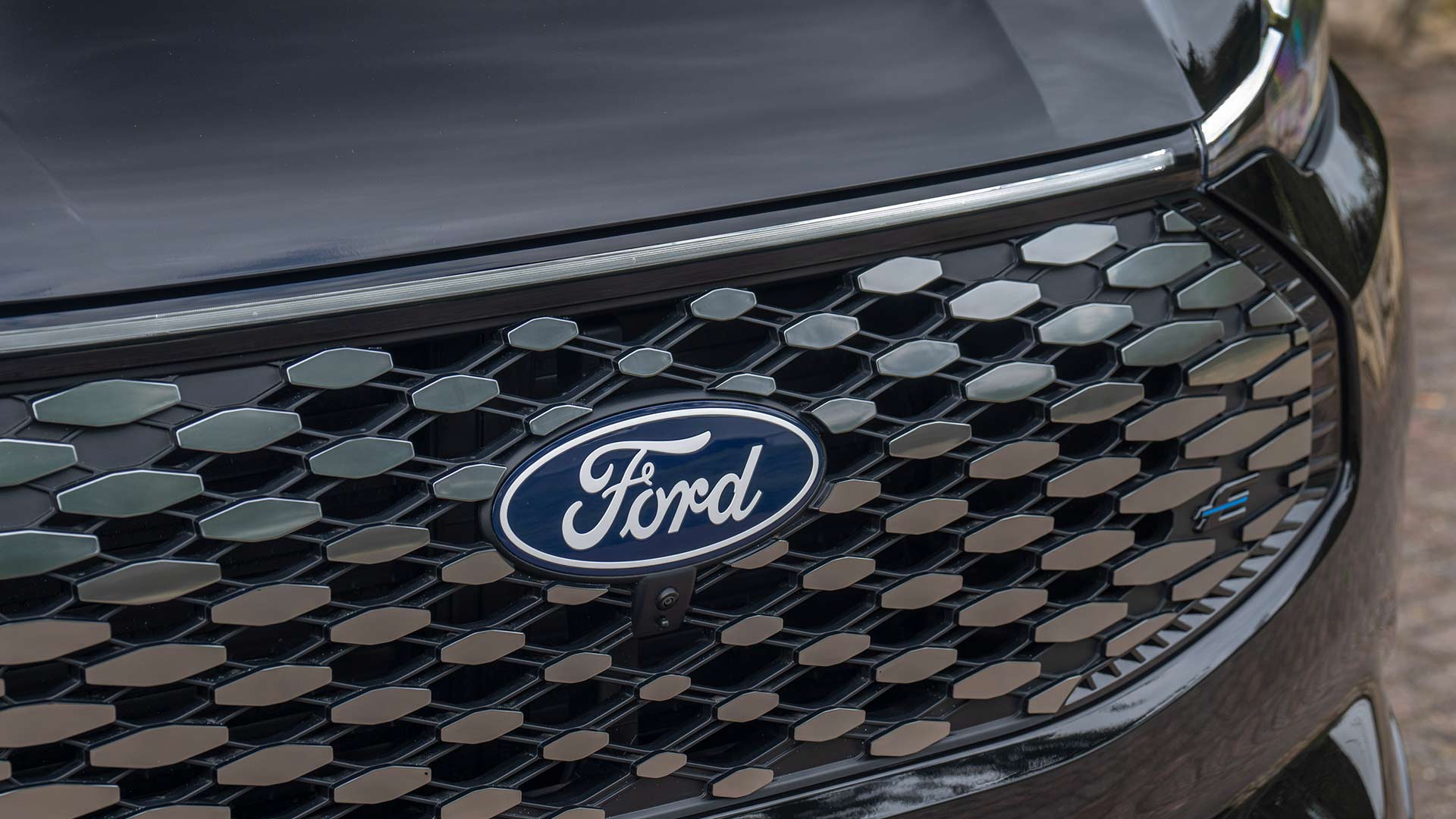 Close-up van het Ford-logo en de grille met patroon op de Ford E-Tourneo Custom.
