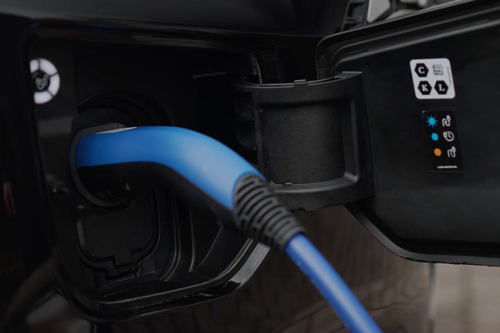 Close-up van een blauwe oplaadkabel die is aangesloten op een oplaadpoort voor elektrische voertuigen.