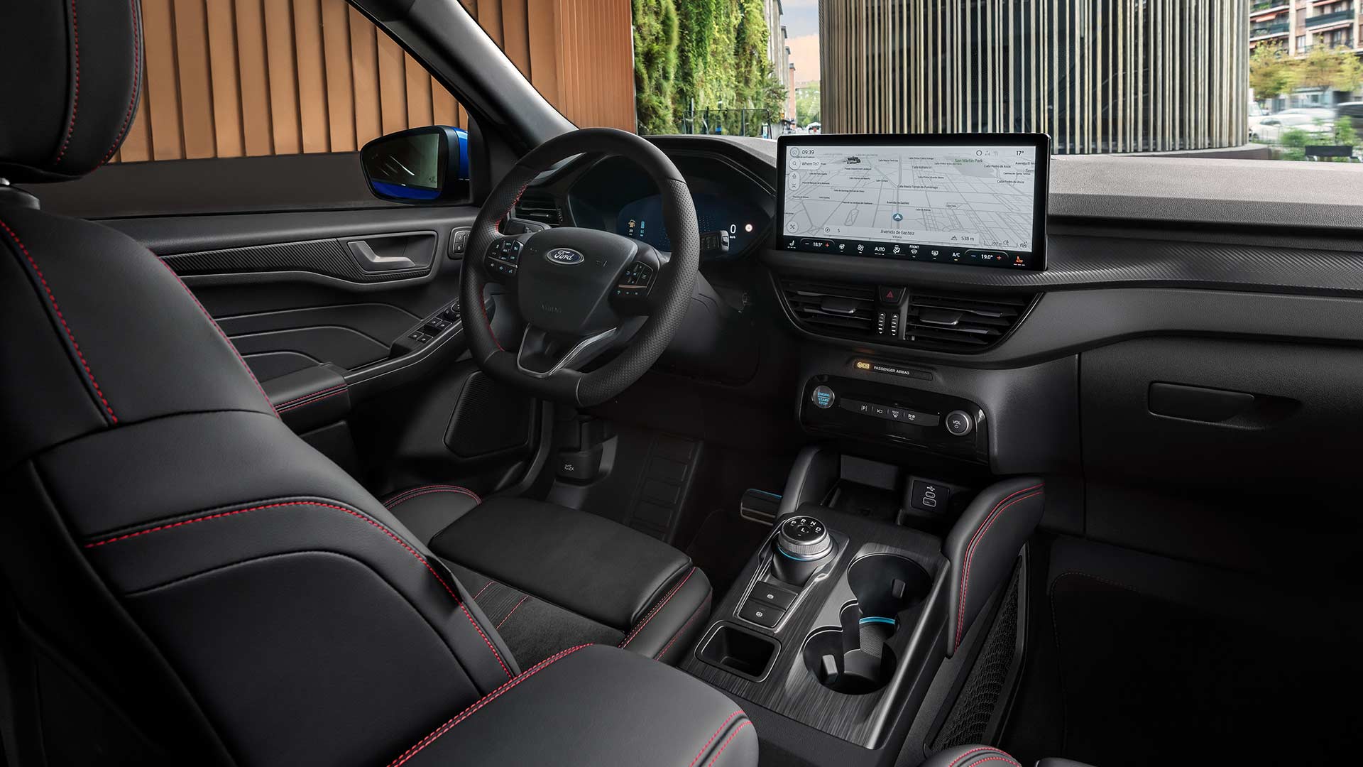Interieur van de Ford Kuga met Ford-logo op het stuurwiel, een groot SYNC® 4-touchscreen en zwarte stoelen met rode stiksels.