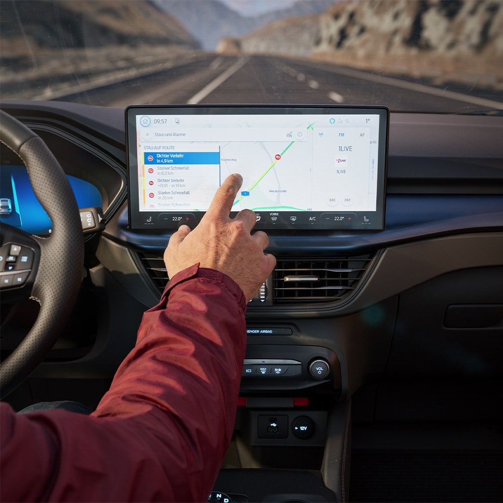 Een bestuurder test de Connected Navigation-functie op het digitale scherm in een Ford Kuga BlueCruise Edition.