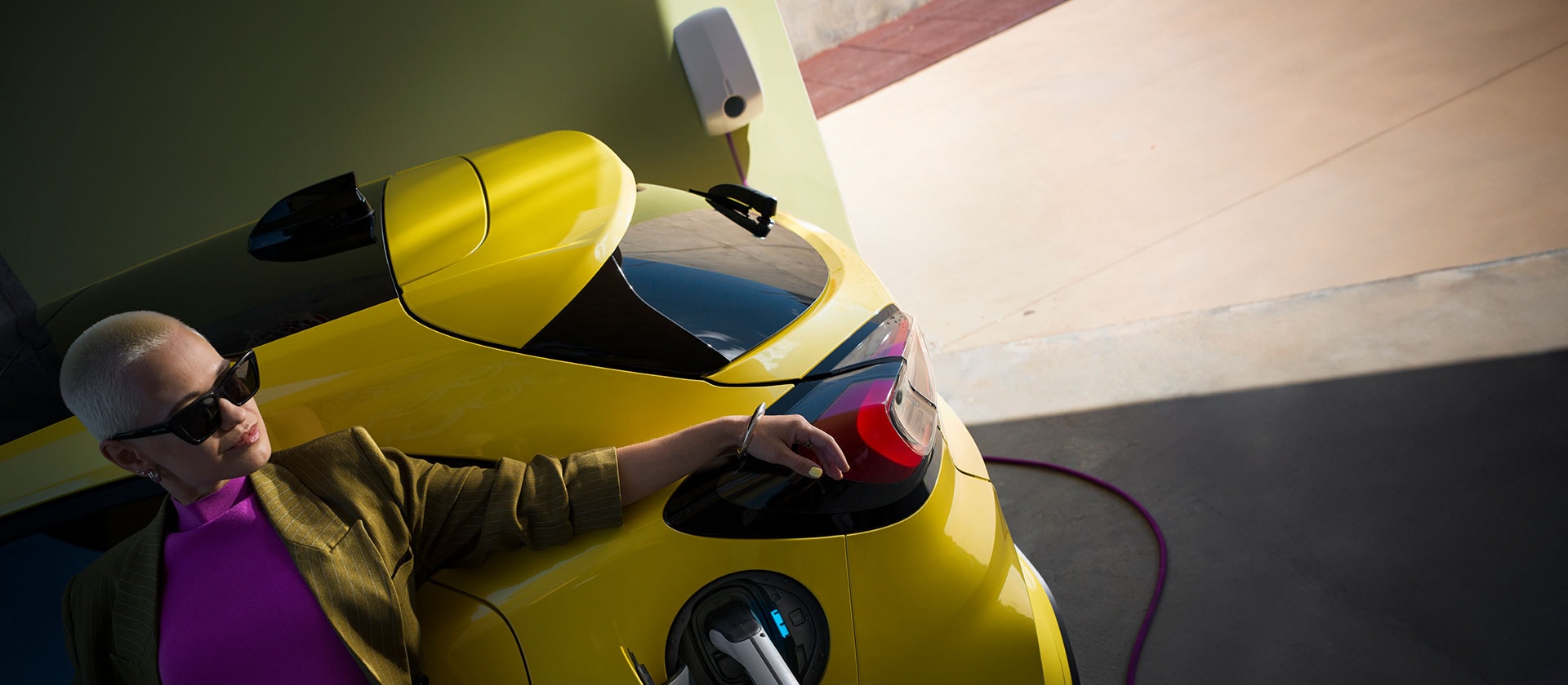 Een close-up van de achterkant van een gele elektrische Ford Puma Gen-E®, aangesloten op een wallbox voor thuisladen.