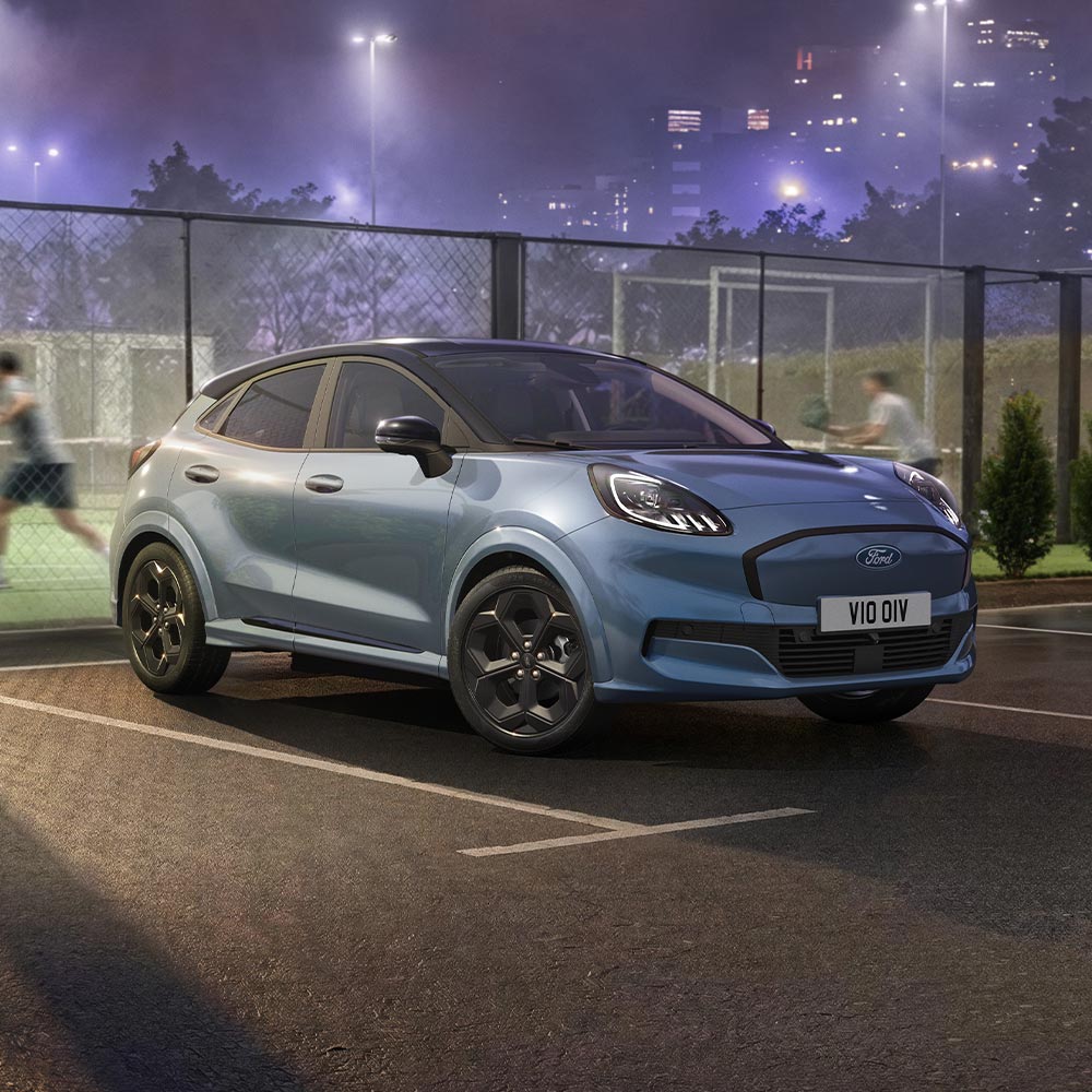 Een limited edition Vapour Blue Ford Puma Gen-E met BlueCruise-technologie, geparkeerd naast een padelbaan in de buitenlucht.