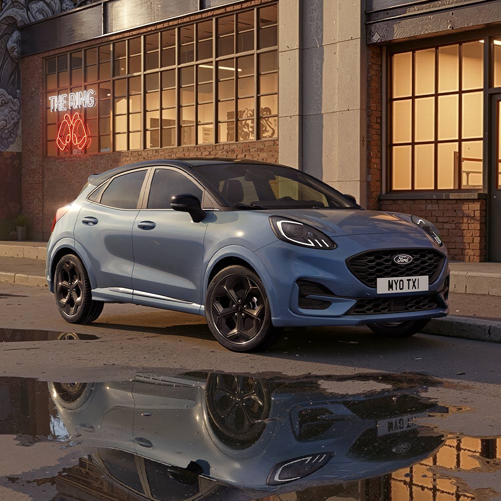 Een limited edition Vapour Blue Ford Puma geparkeerd op een slecht verlichte stadsweg 's nachts.