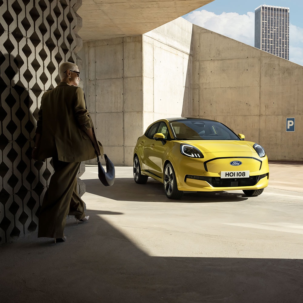 Een persoon loopt naar de nieuwe elektrische Ford Puma Gen-E® in het geel.