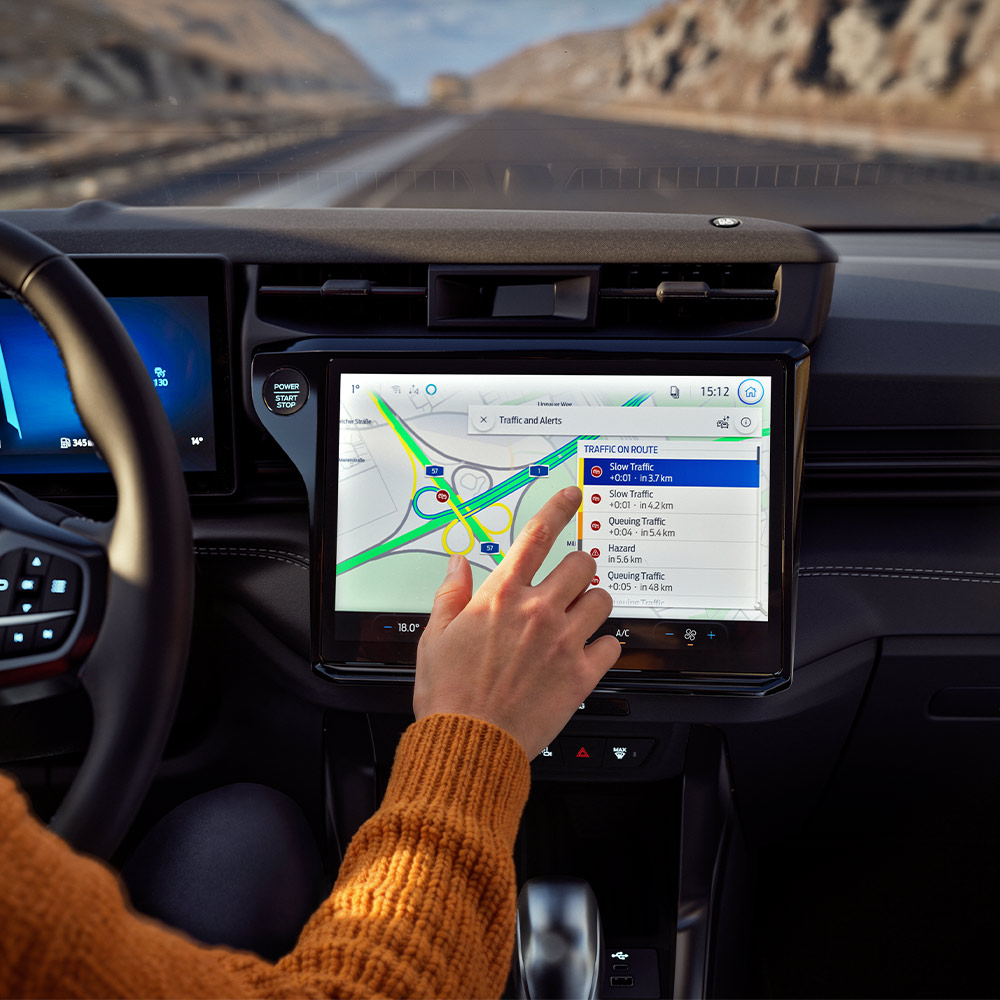 Een bestuurder test de verbonden navigatie op het digitale scherm in een Ford Puma BlueCruise Edition.