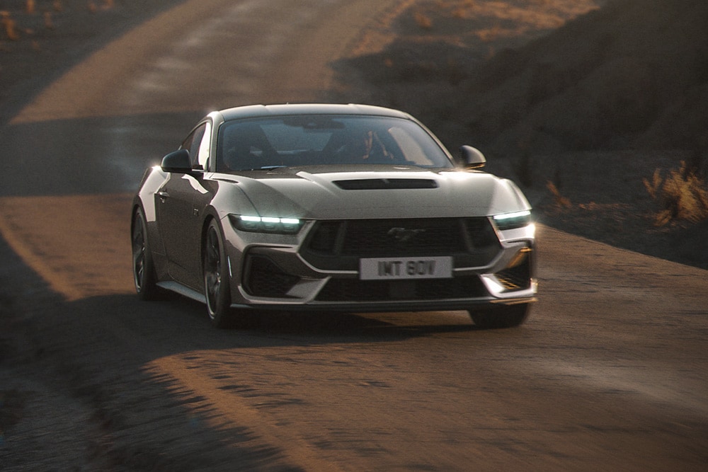 Grijze Ford Mustang Nite Pony die over een weg rijdt