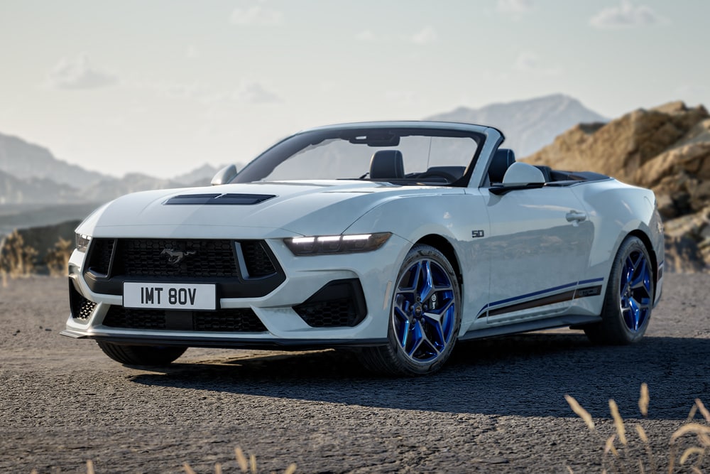 Zijprofiel van een witte Ford Mustang California Special op een weg tussen de heuvels