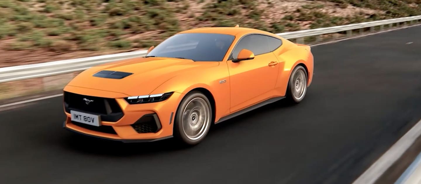 Ford Mustang GT Fastback in Orange Fury rijdend op een bergweg
