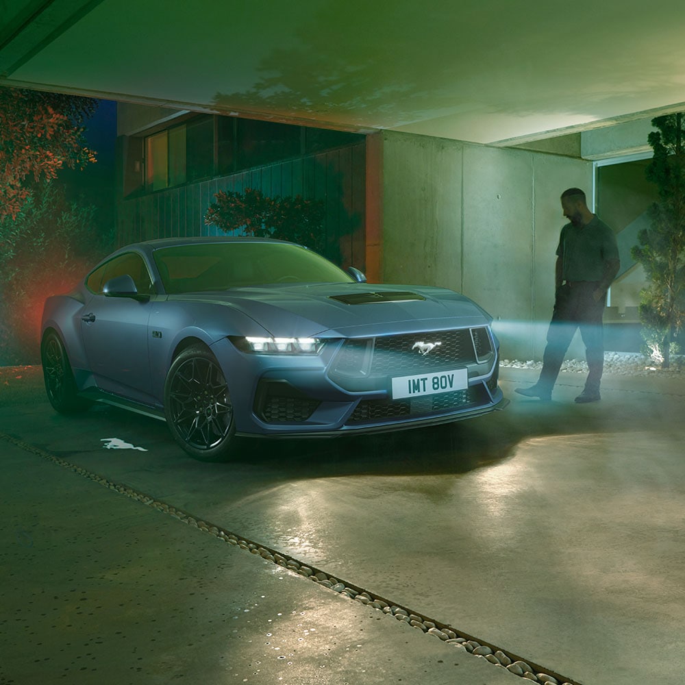 Man die een geparkeerde Ford Mustang nadert met brandende koplampen, waarbij het welkomstlicht wordt geactiveerd