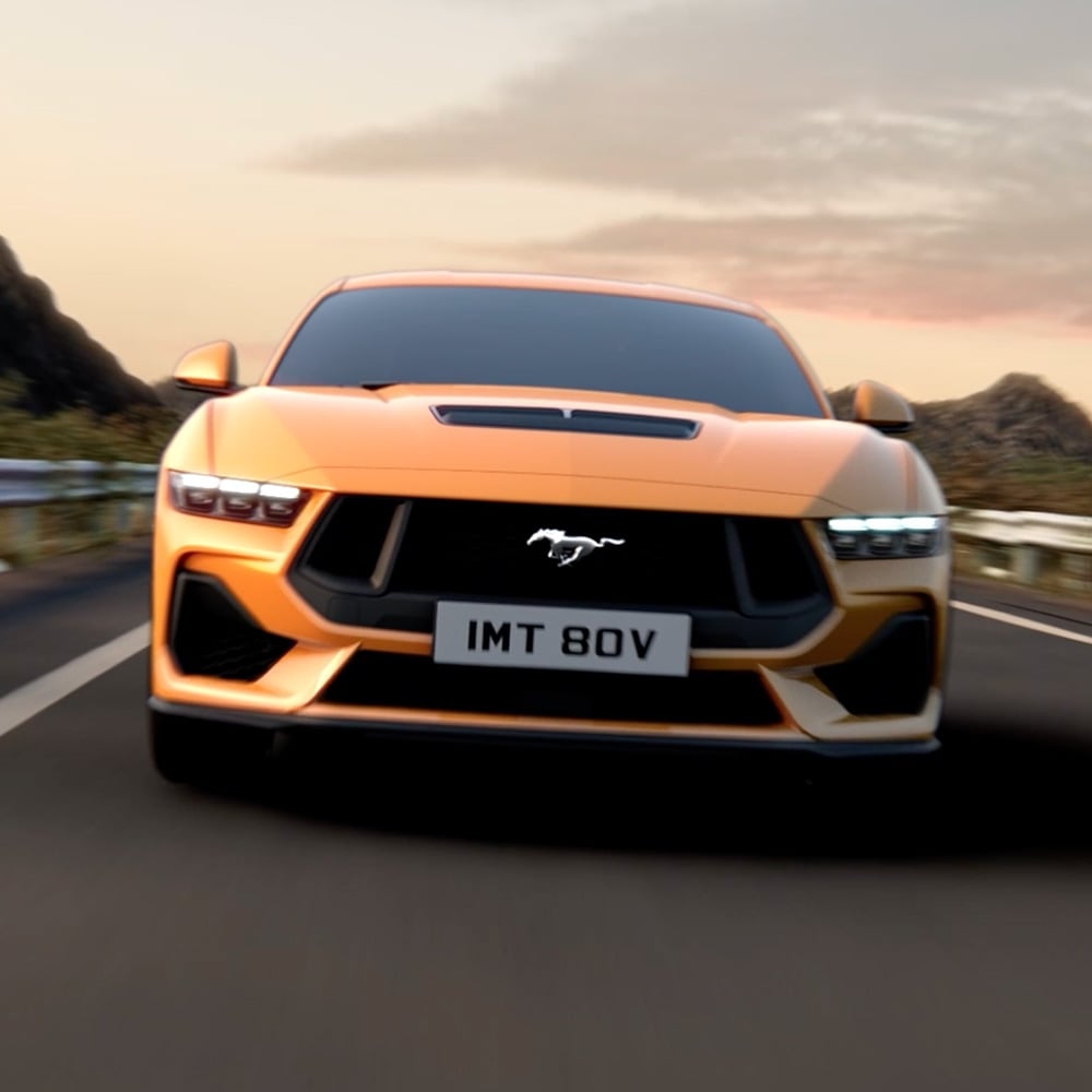 Vooraanzicht van een oranje Ford Mustang met close-up van de koplampen, grille en Mustang-badge