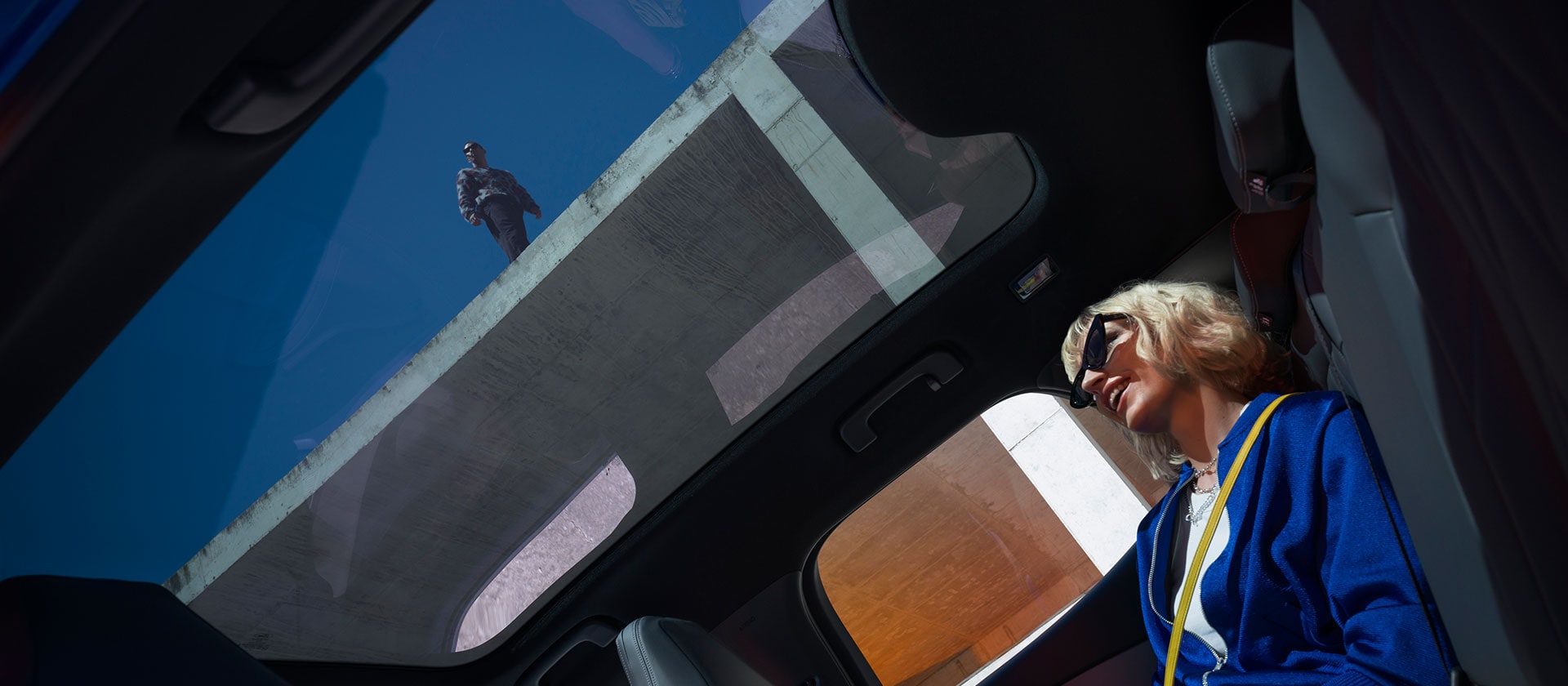 Een vrouw zit op de bestuurderszetel van een geparkeerde Ford Capri®, met zicht op het stuur en een groot SYNC® Move-touchscreen.