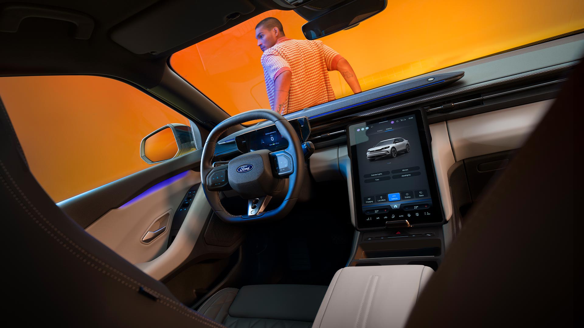 Het interieur van de Ford Capri, geparkeerd in een gele fotostudio. Een man leunt op de voorkant van de auto.