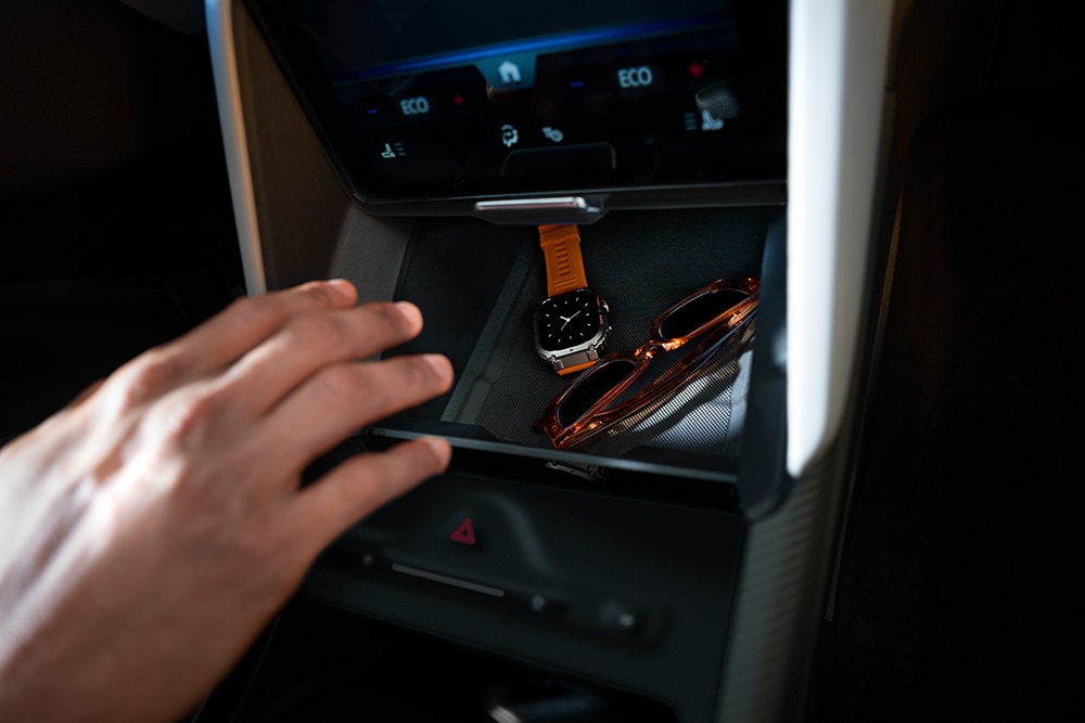 Een hand reikt naar de My Private Locker verborgen opslagsruimte in de Ford Capri®, met zicht op een horloge en een zonnebril binnenin.