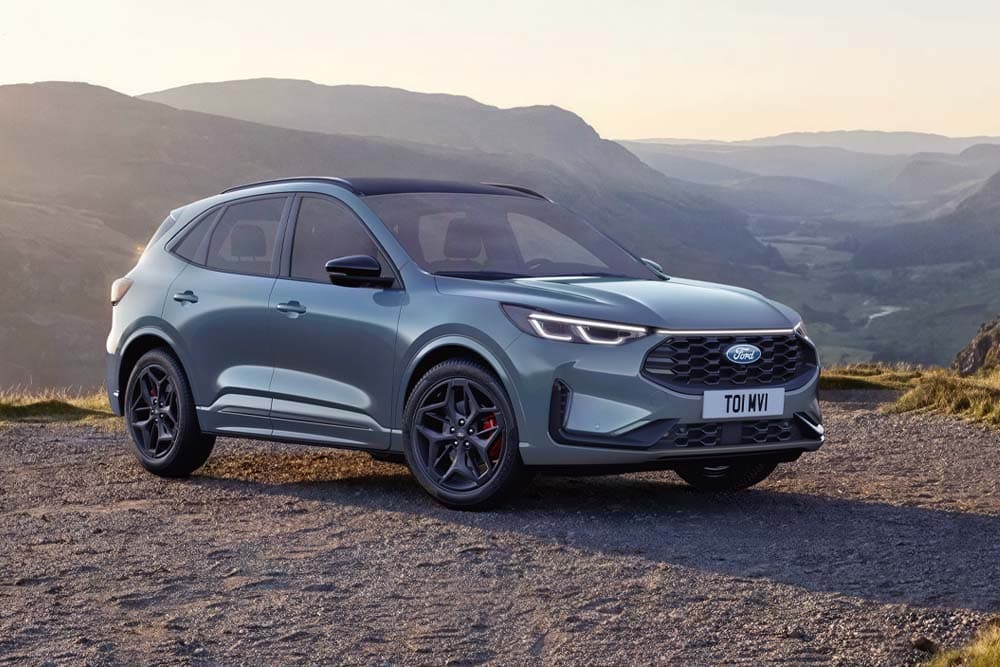 Een grijze Ford Kuga geparkeerd op een onverharde bergweg bij zonsondergang.