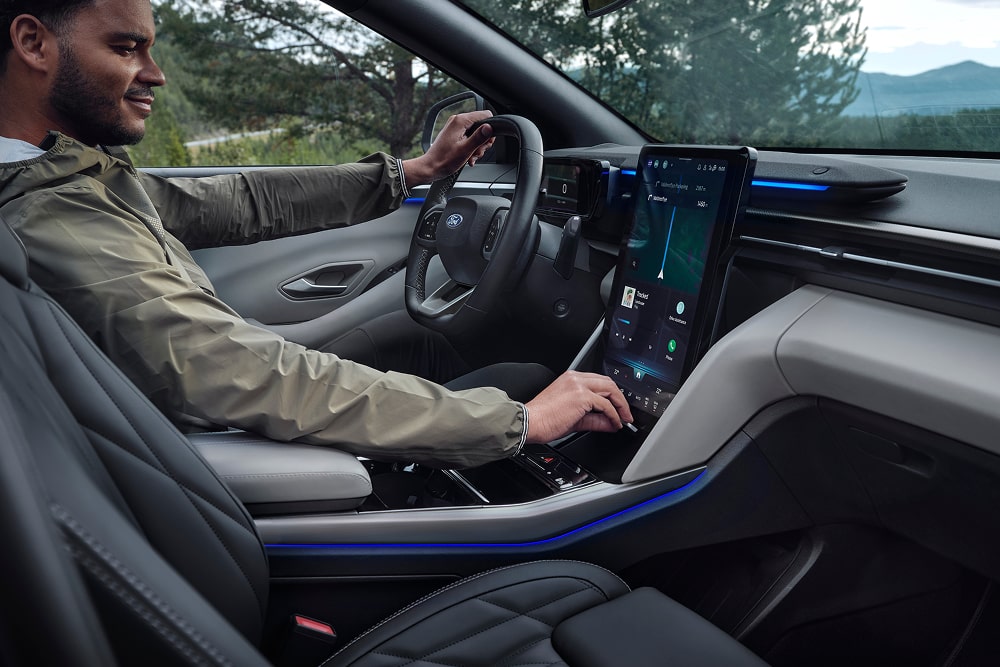 Bestuurder gebruikt het infotainmentsysteem met aanraakscherm in de Ford Explorer SUV voor het gezin.