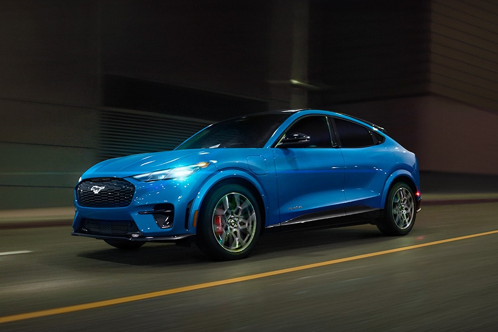 Een blauwe Ford Mustang Mach-E GT elektrische sportwagen over een open weg.