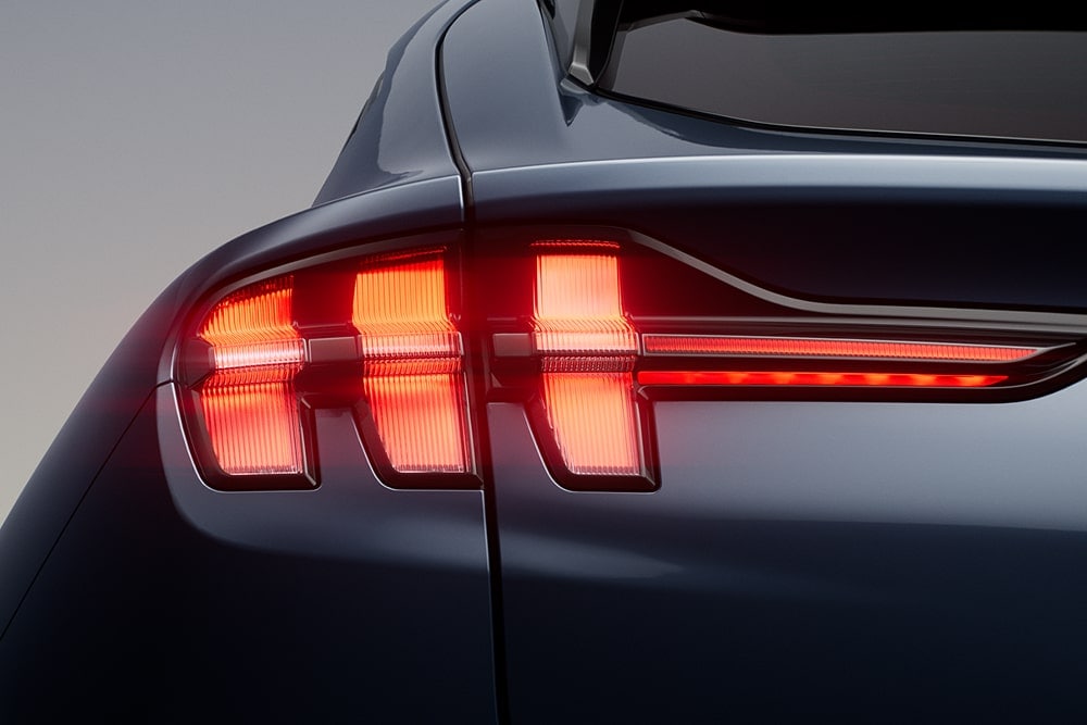 Close-up van verlichte driedubbele achterlichten op een Ford Mustang Mach-E sportwagen.