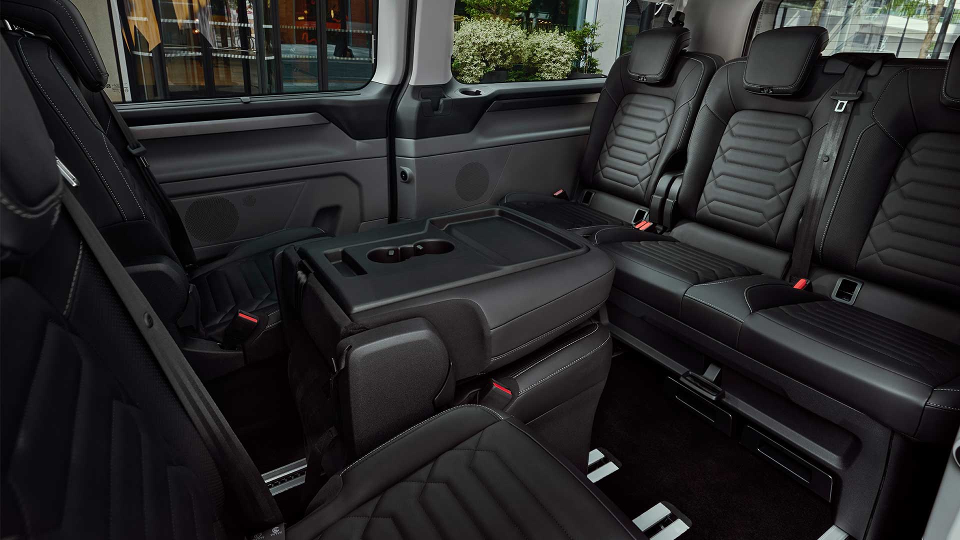 Interieur van de Ford Tourneo Custom, met flexibele zetels en een kleine tafel.