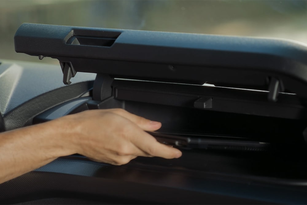 Een hand reikt in een compartiment boven de bestuurderszetel in de Ford Tourneo Custom.